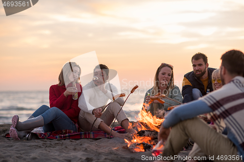 Image of Group Of Young Friends Sitting By The Fire at beach