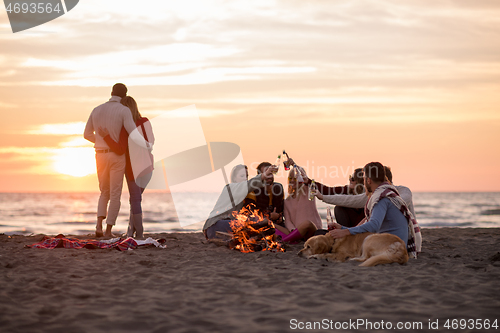 Image of Couple enjoying with friends at sunset on the beach