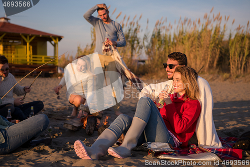 Image of Couple enjoying with friends at sunset on the beach