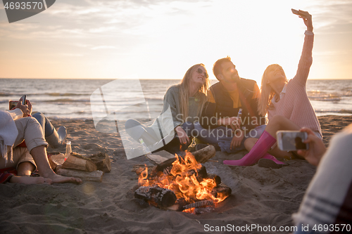 Image of Friends having fun at beach on autumn day