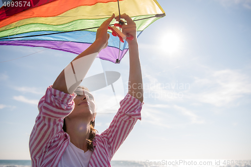 Image of Young Woman with kite at beach on autumn day