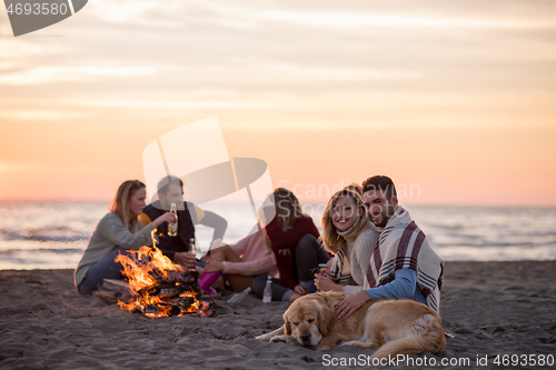 Image of Couple enjoying with friends at sunset on the beach