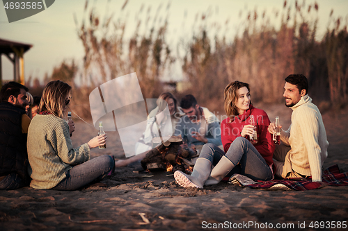 Image of Couple enjoying with friends at sunset on the beach