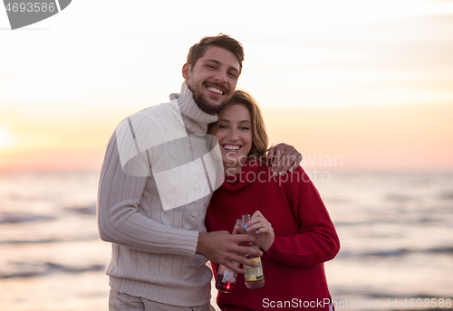 Image of Couple hugging and drinking beer together at the beach