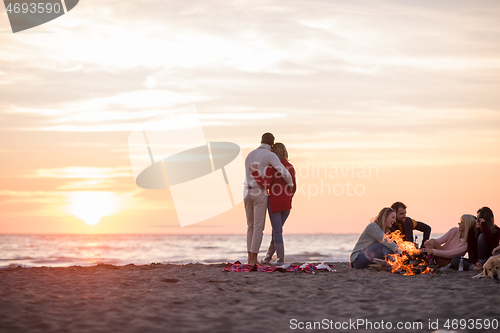 Image of Couple enjoying with friends at sunset on the beach