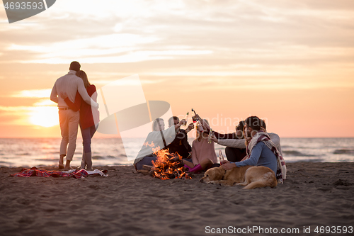 Image of Couple enjoying with friends at sunset on the beach