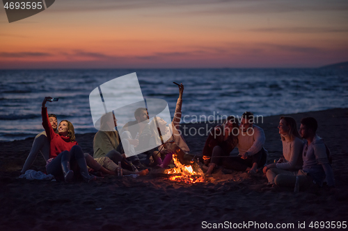 Image of a group of friends enjoying bonfire on beach