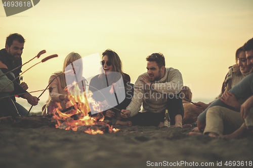 Image of Group Of Young Friends Sitting By The Fire at beach