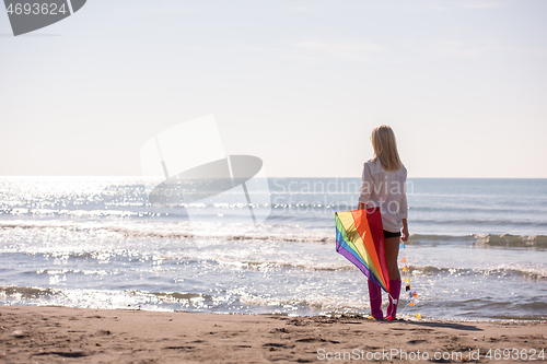 Image of Young Woman with kite at beach on autumn day