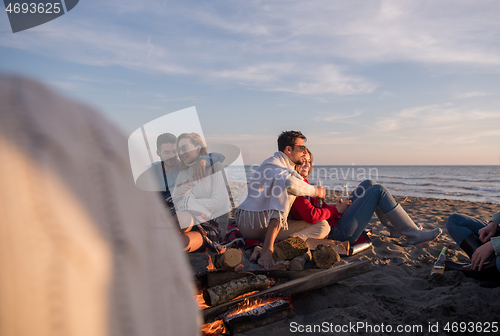 Image of Couple enjoying with friends at sunset on the beach