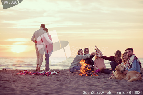 Image of Couple enjoying with friends at sunset on the beach