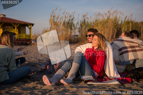 Image of Couple enjoying with friends at sunset on the beach