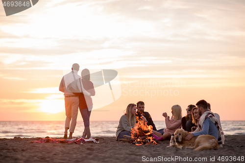 Image of Couple enjoying with friends at sunset on the beach