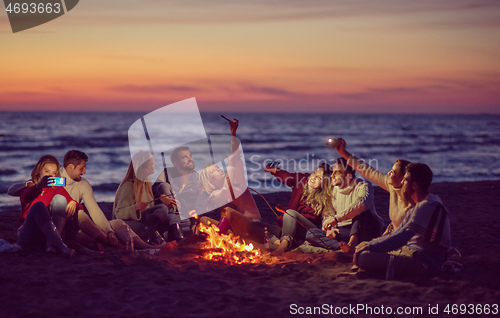 Image of a group of friends enjoying bonfire on beach