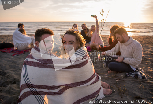 Image of Couple enjoying with friends at sunset on the beach