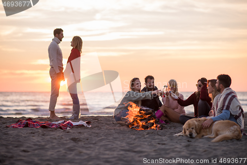 Image of Couple enjoying with friends at sunset on the beach