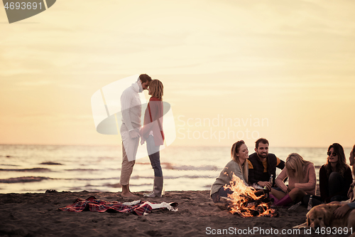 Image of Couple enjoying with friends at sunset on the beach