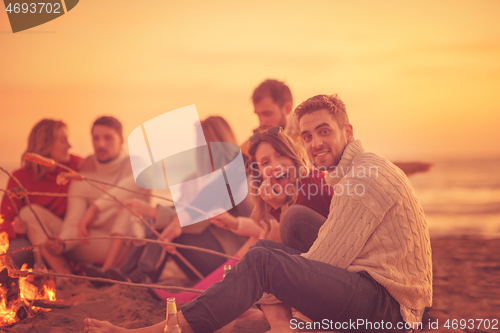 Image of Group Of Young Friends Sitting By The Fire at beach