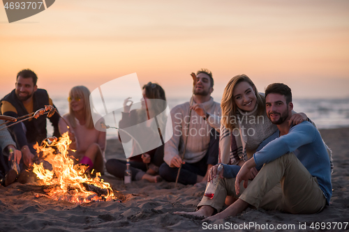 Image of Group Of Young Friends Sitting By The Fire at beach