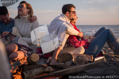 Image of Couple enjoying with friends at sunset on the beach