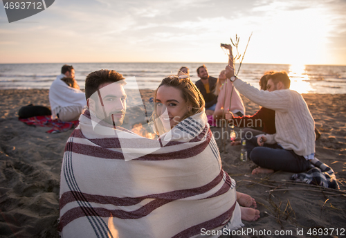 Image of Couple enjoying with friends at sunset on the beach