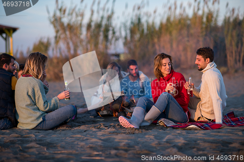 Image of Couple enjoying with friends at sunset on the beach