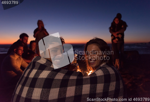 Image of Couple enjoying with friends at sunset on the beach