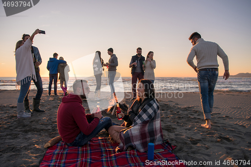 Image of Couple enjoying with friends at sunset on the beach