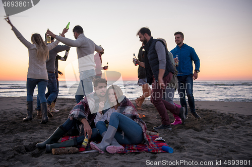 Image of Couple enjoying with friends at sunset on the beach