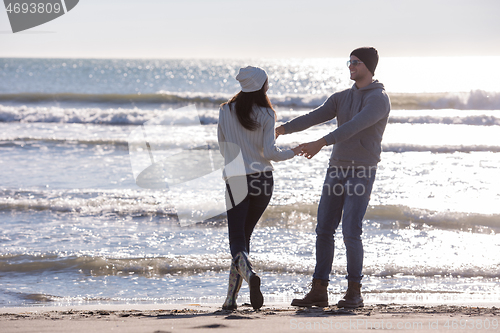 Image of Loving young couple on a beach at autumn sunny day