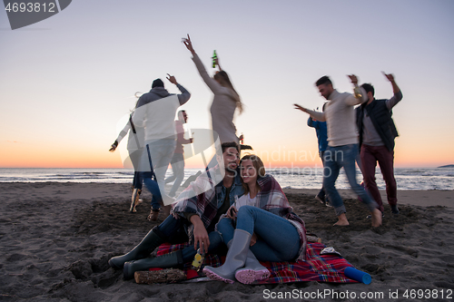 Image of Couple enjoying with friends at sunset on the beach