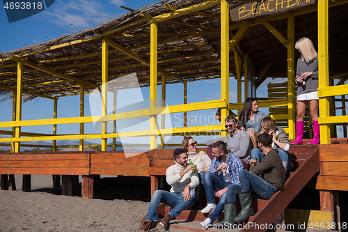 Image of Group of friends having fun on autumn day at beach