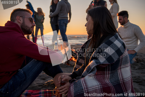 Image of Couple enjoying with friends at sunset on the beach