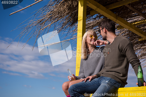 Image of young couple drinking beer together at the beach