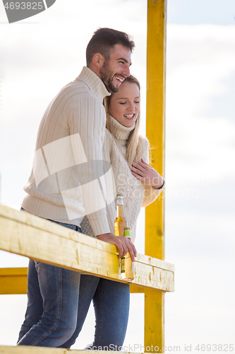 Image of young couple drinking beer together at the beach