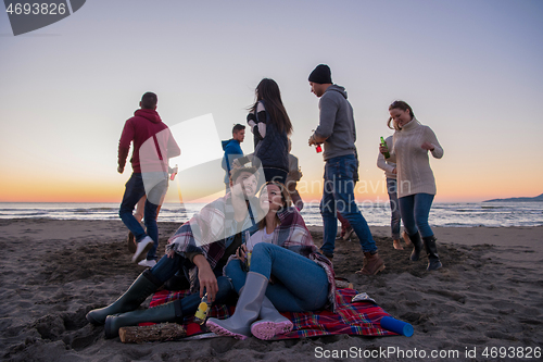 Image of Couple enjoying with friends at sunset on the beach