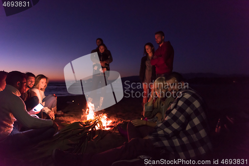 Image of Couple enjoying with friends at sunset on the beach