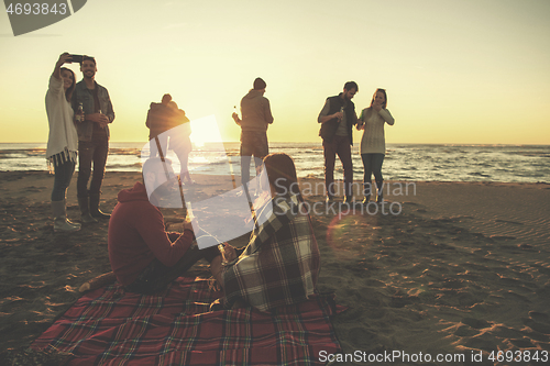 Image of Couple enjoying with friends at sunset on the beach