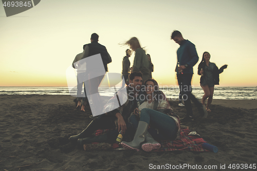 Image of Couple enjoying with friends at sunset on the beach