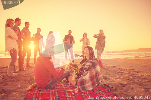 Image of Couple enjoying with friends at sunset on the beach