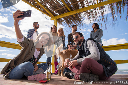 Image of Group of friends having fun on autumn day at beach