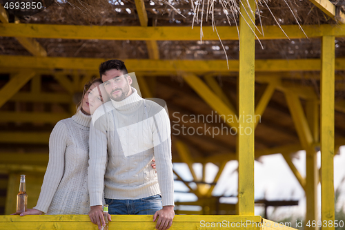 Image of young couple drinking beer together at the beach