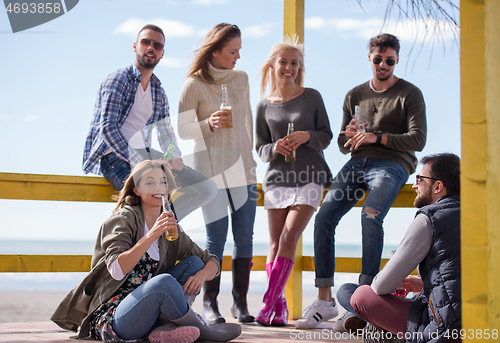 Image of Group of friends having fun on autumn day at beach