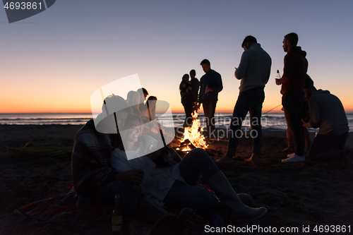 Image of Couple enjoying bonfire with friends on beach