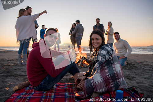 Image of Couple enjoying with friends at sunset on the beach