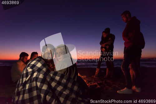 Image of Couple enjoying with friends at sunset on the beach