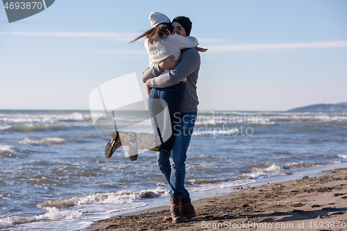 Image of Loving young couple on a beach at autumn sunny day