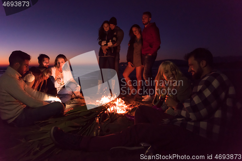 Image of Couple enjoying with friends at sunset on the beach