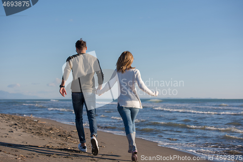 Image of Loving young couple on a beach at autumn sunny day