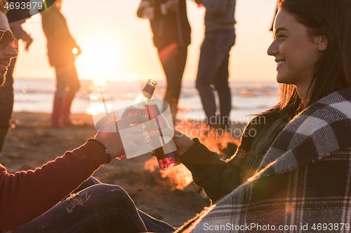 Image of Couple enjoying with friends at sunset on the beach